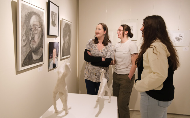 Female students smiling while looking at art in the gallery