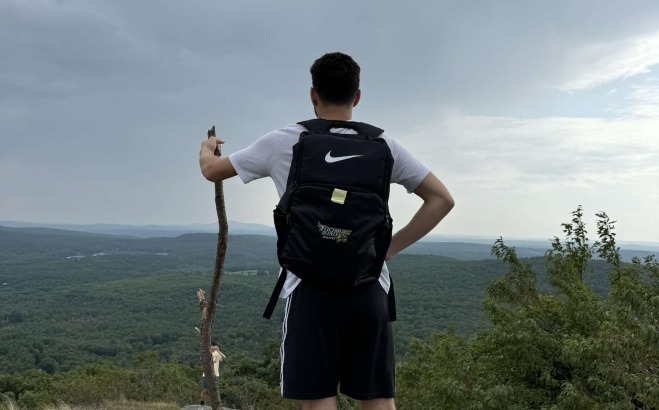 Logan Cashman's back standing on top of mountain