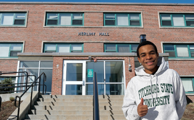 Christian Dedier in front of Herlihy Hall near the steps giving thumbs up