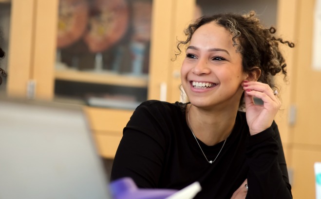Smiling female student in classroom lab with laptop