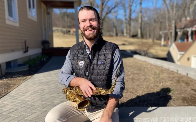 Jack Mellish sitting outside with sax.