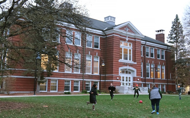 Students playing game in the grass in front of Percival Hall