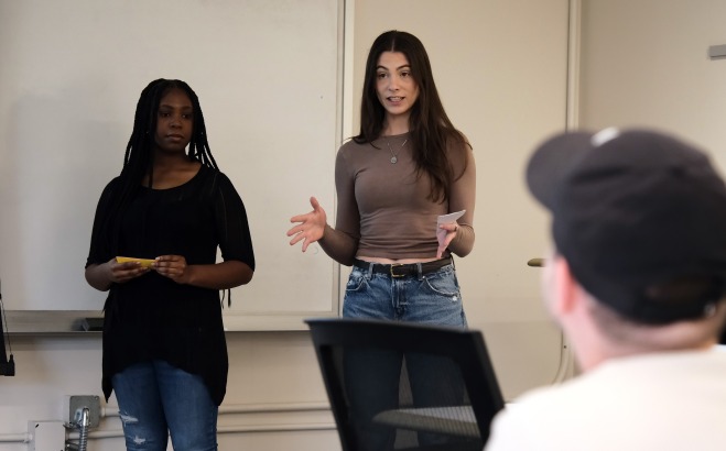 Two female students giving presentation in front of class