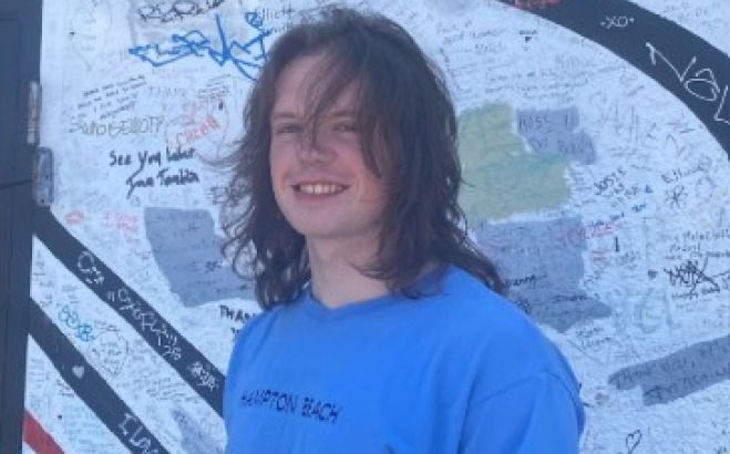 Liam Dewar outside in front of a graffiti wall. 