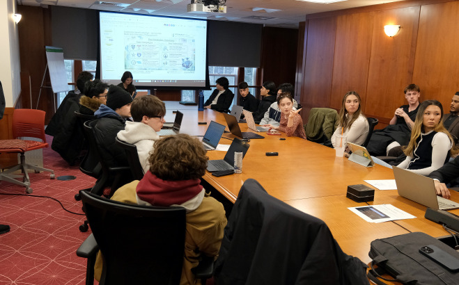 Business students at conference table with male presenting to class.