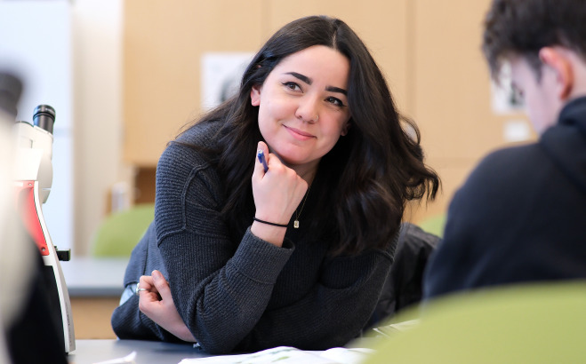 Smiling female student at table in lab.