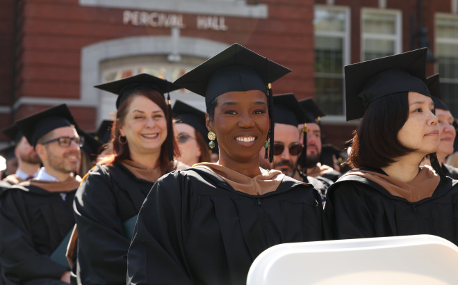Smiling grad students on quad at commencement.