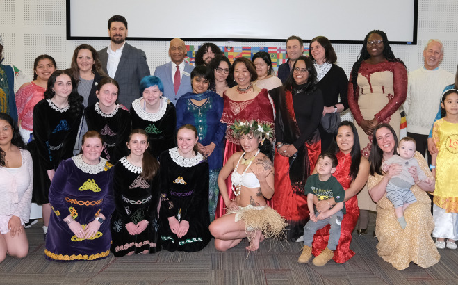 International night group photo of staff and students in cultural attire.