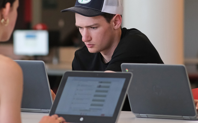 Students on laptops in library. 