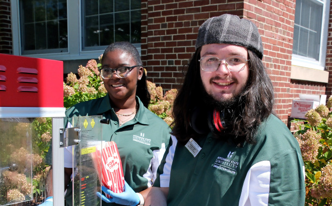 Student workers outside scooping popcorn into bags.