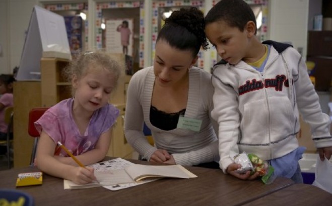 Student helping children with writing