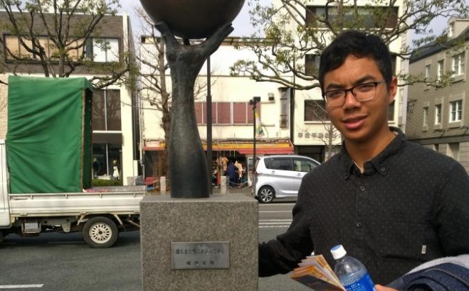 Brandon Voeuk next to a statue in Japan