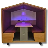 Covered wooden booth with bench seats and table with a small pendent light emitting a soft purple light