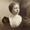 Sepia-toned vintage portrait of a woman in early 20th-century attire with a high-collared blouse.