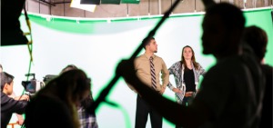 A man and woman being photographed a green screen
