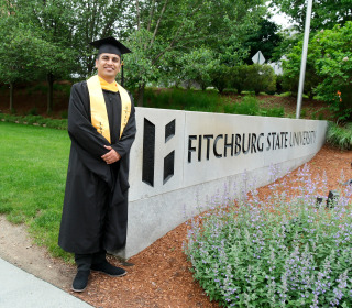 Ali Raza graduation in front of Hammond Hall cap and gown