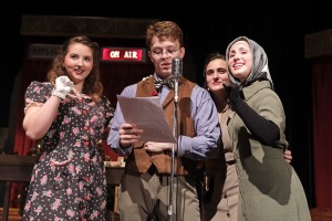 One male and three female actors performing in front of the microphone on stage