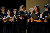 Group of females singing on stage in Weston Auditorium. 