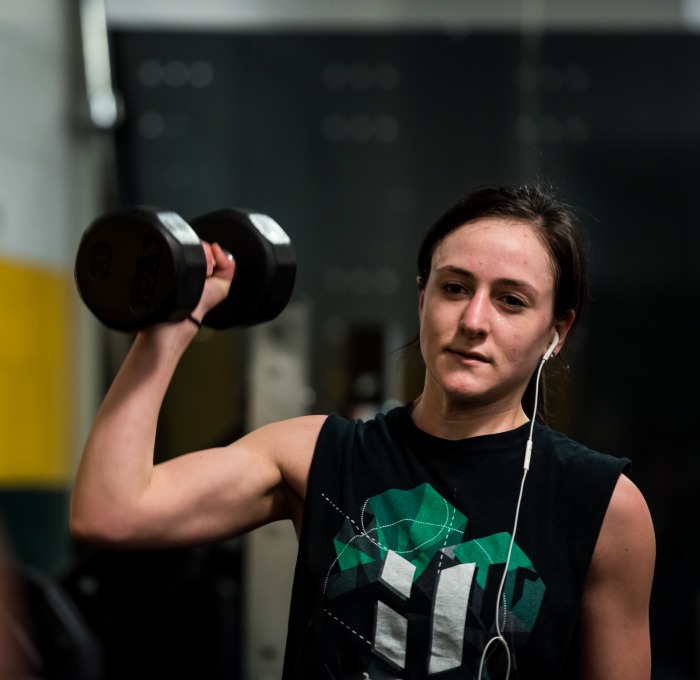 a female student lifts weights in the rec center
