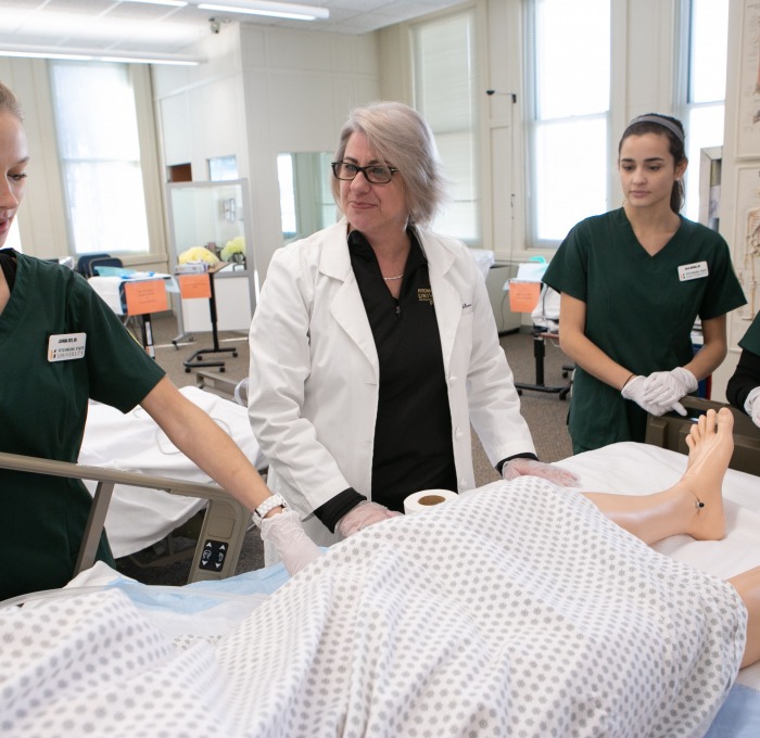 Students care for a patient in a nursing classroom