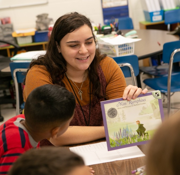 Student teacher in McKay classroom with students and book