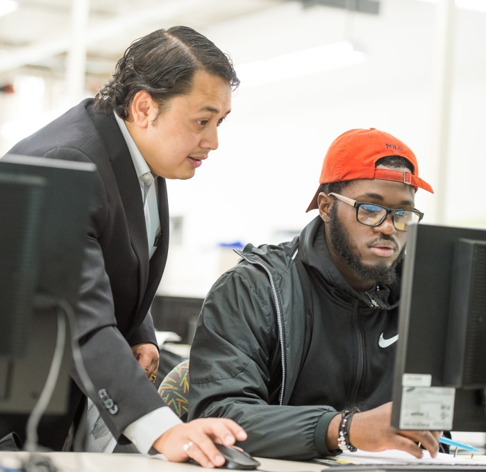 Engineering professor Nirajan Mani and student at computer in classroom