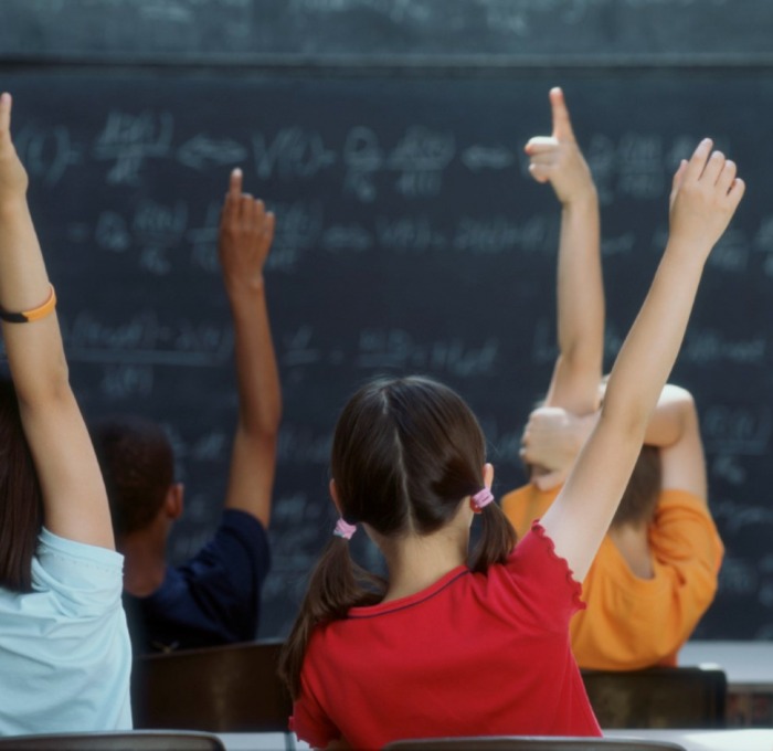 young students with hands raised