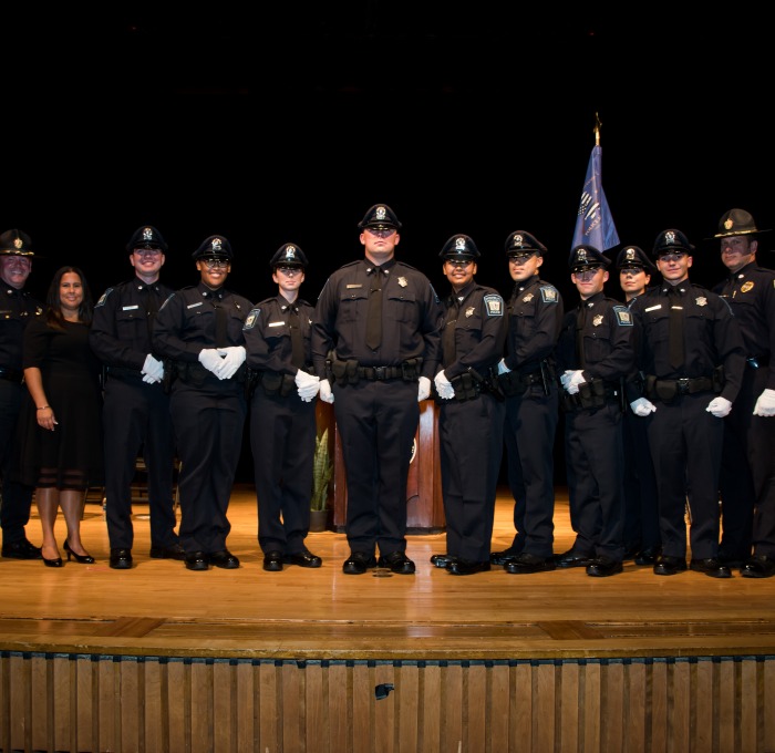 Police graduates standing in group photo on the stage after ceremony