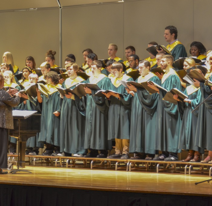 Students in the choir singing on stage in auditorium