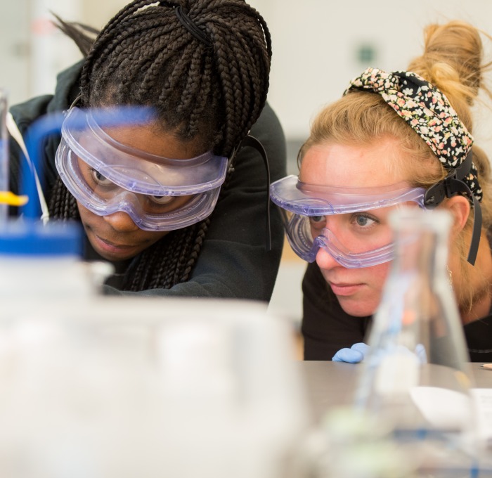 Students with goggles doing an experiment in a science lab