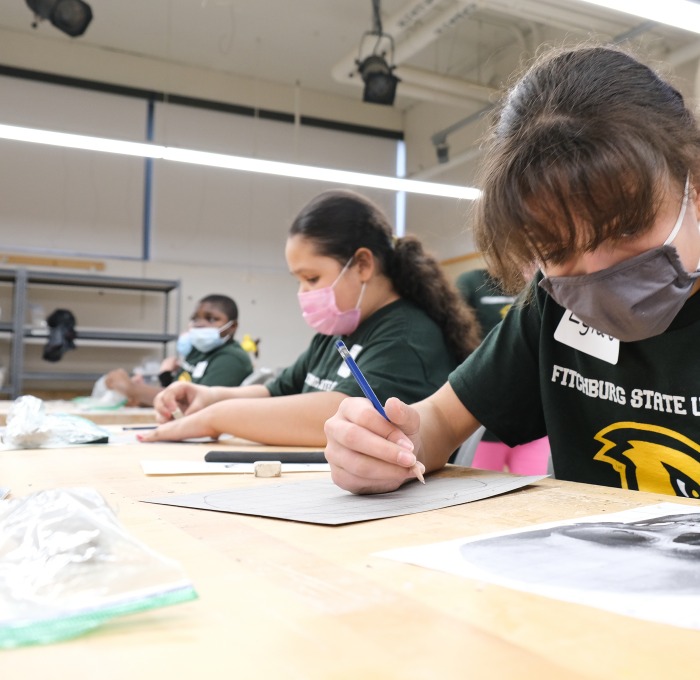Two female and one male Future Falcon middle school students working on drawings in a classroom