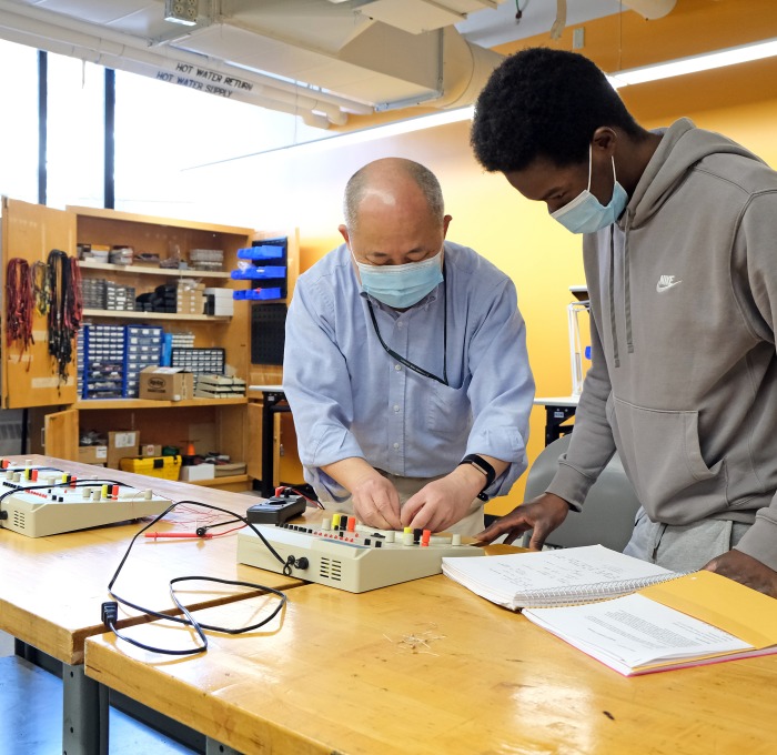 Male professor and student working on electronics in classrom