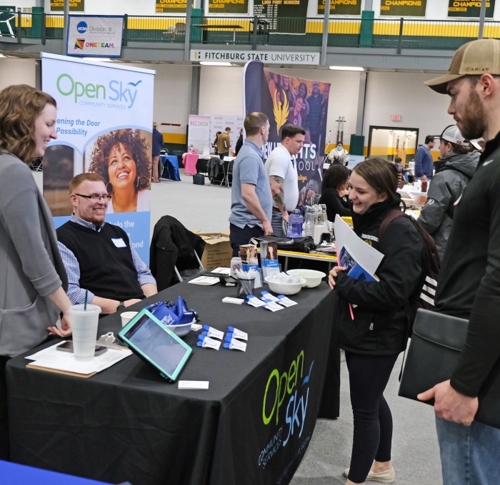 Male and female student talking to employers at booth at career fair in rec center