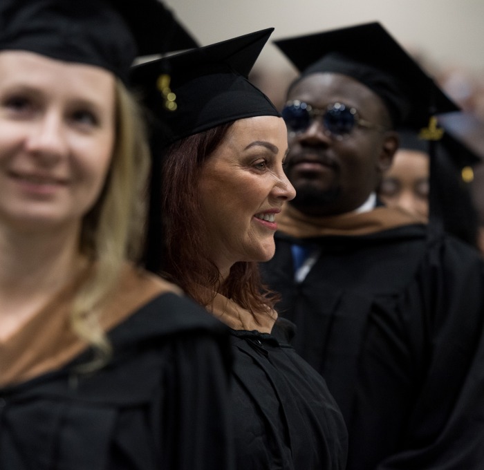 Two female and one male student at graduate commencement in the rec center