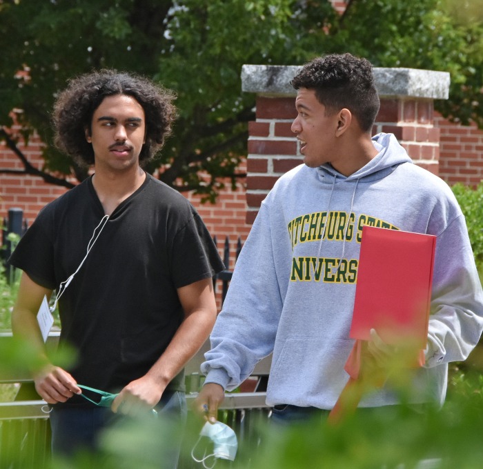 Male students walking on campus across bridge