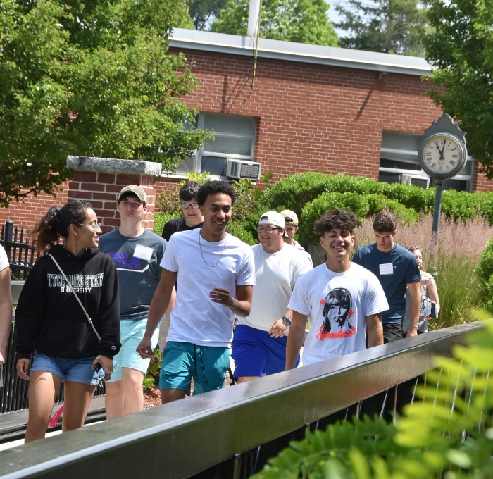 Happy group of students at orientation walking across bridge to Holmes