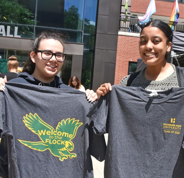 Students holding up t-shirts at orientation outside in front of Hammond Hall