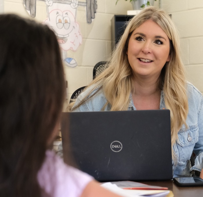 Elementary school counselor talking to student behind laptop