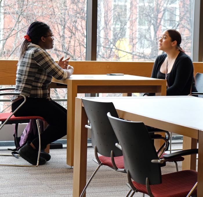 Females talking at table in library