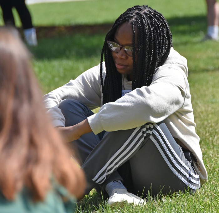 Student on quad at orientation sitting in grass