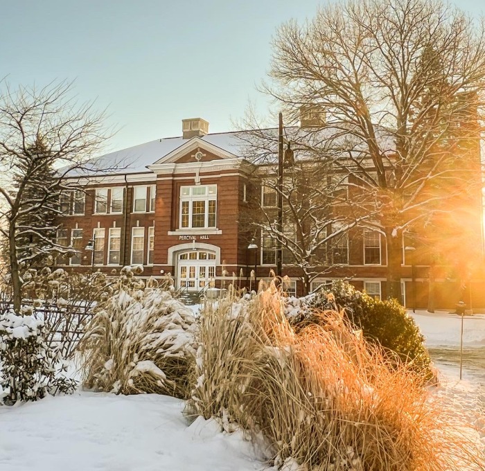 Snowy Percival Hall and Quad with sun shining through trees