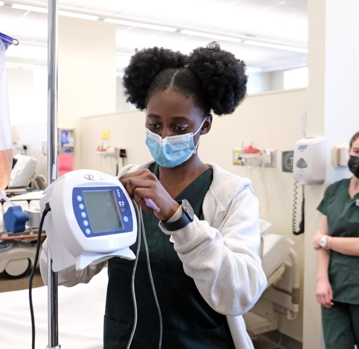 Nursing student in the lab hanging a bag of fluids