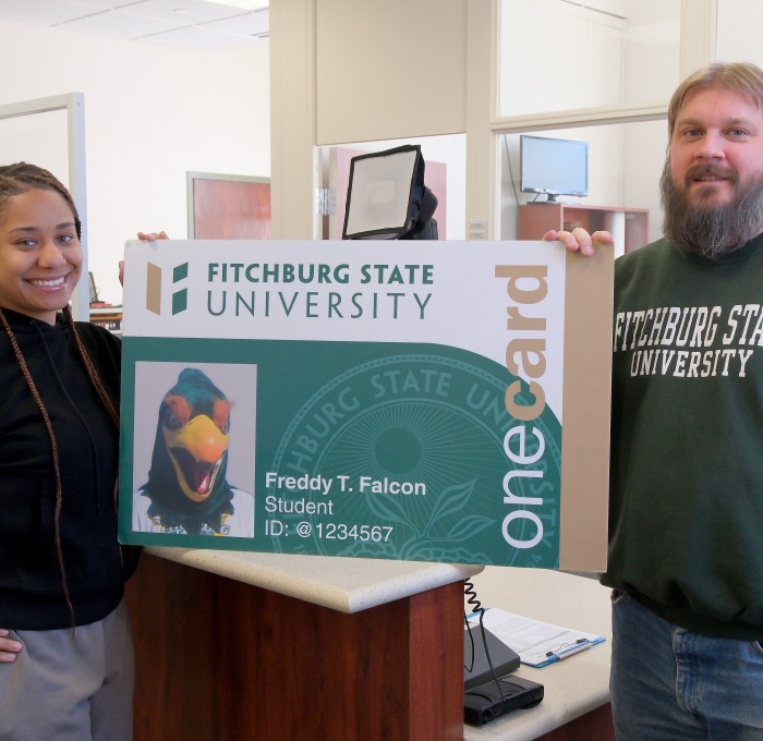 OneCard office Darryl and student worker holding big onecard cutout