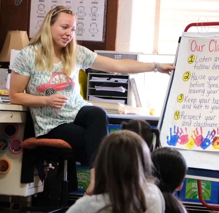 Teacher in a first grade classroom with students discussing rules