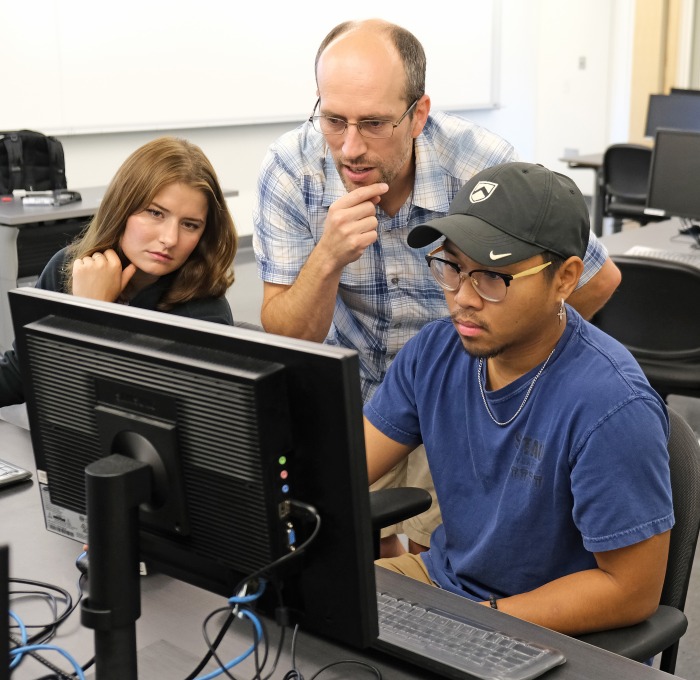 Male teacher with students at computer