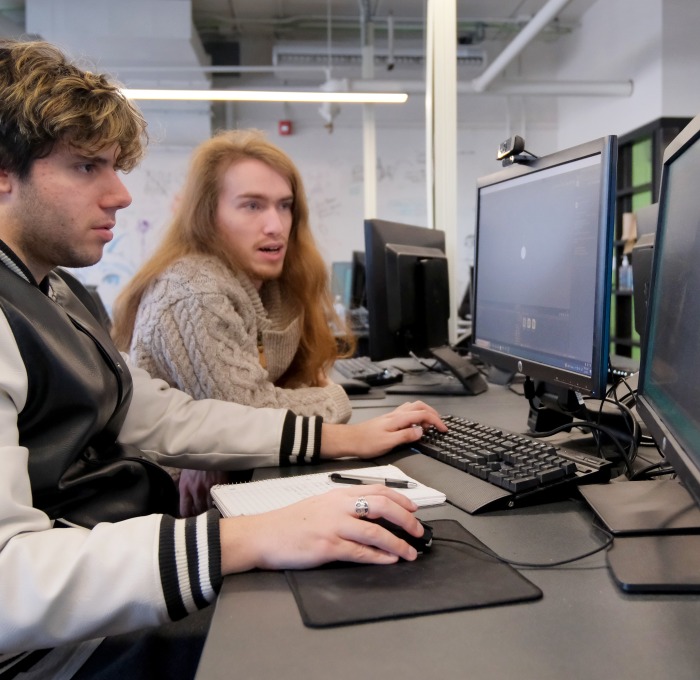Two male students working on computers in a classroom