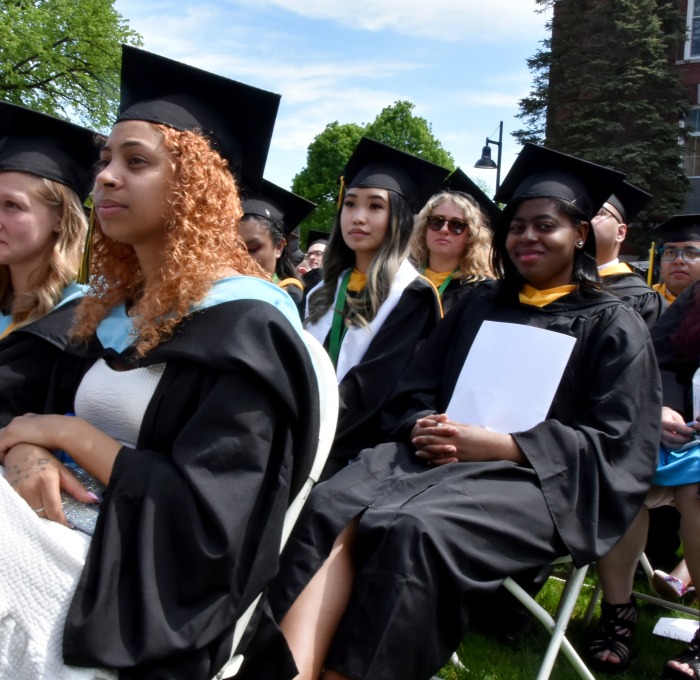 Students sitting at undergrad commencement outside on quad