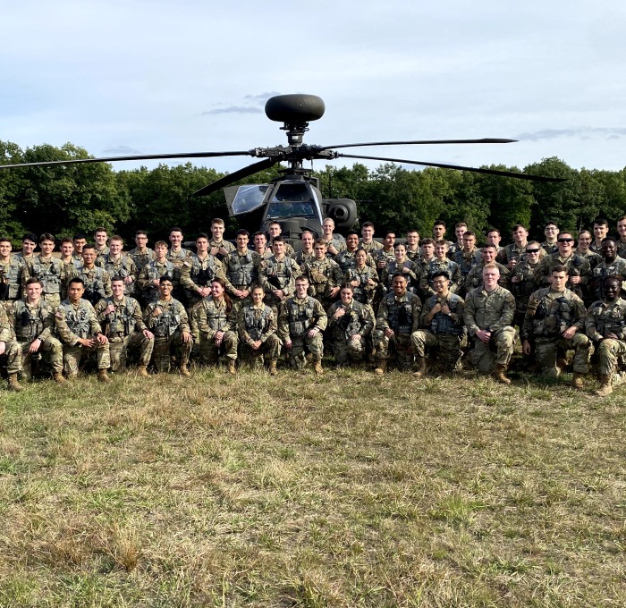 Army ROTC group in front of a helicopter in a field