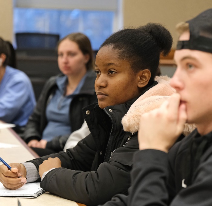 Three female and one male student listening intently in a classroom