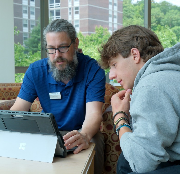 Senior associate registrar Mark LeBlanc working with male student on tablet to register for classes